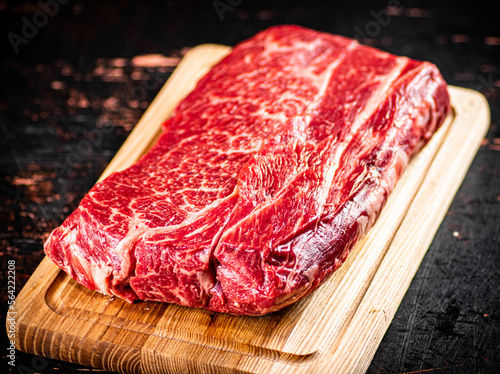 A piece of fresh raw beef on a cutting board. 