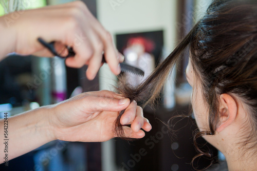 At a hair dresser, salon, detail of hands holding a comb and finishing a woman´´ s hair style. No face visible. Photo of a professional at work. 