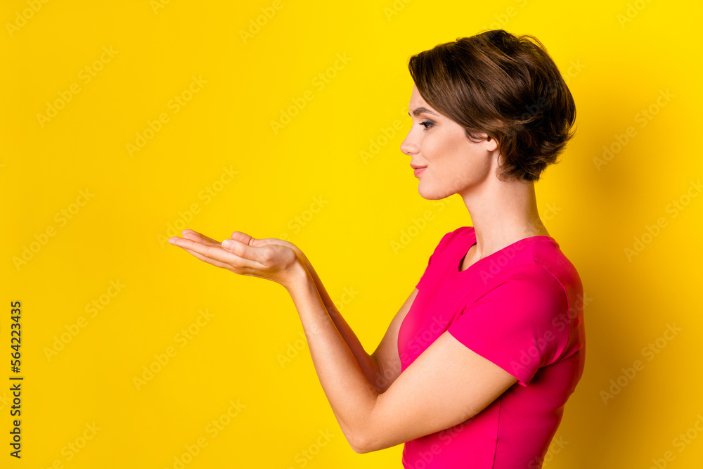 Profile side photo of adorable lovely lady two arms hold blank space interesting proposition isolated on yellow color background Profile side photo of adorable lovely lady two arms hold blank space interesting proposition isolated on yellow color background