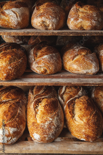 Assortments of bread, freshly baked on wooden shelves. Bakery shelves full of breads. Bakery goods
