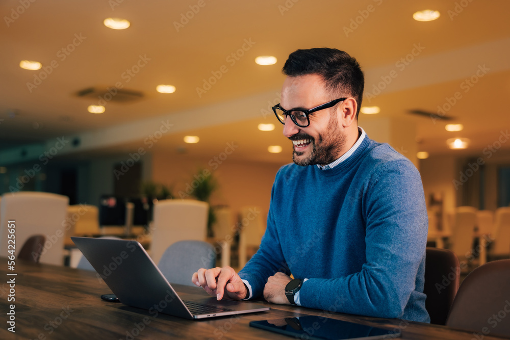 Cheerful businessman having an online meeting with a colleague, sitting at the office. Cheerful businessman having an online meeting with a colleague, sitting at the office.