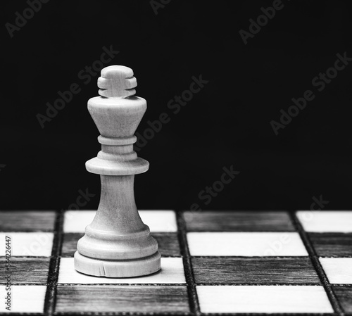 Lone white king on chessboard, black background