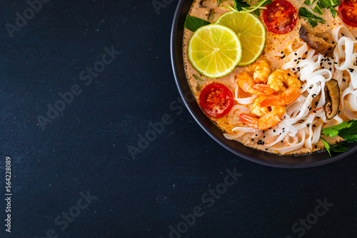 Tom Yum - Thai soup with prawns, shiitake mushrooms and noodles on wooden table 