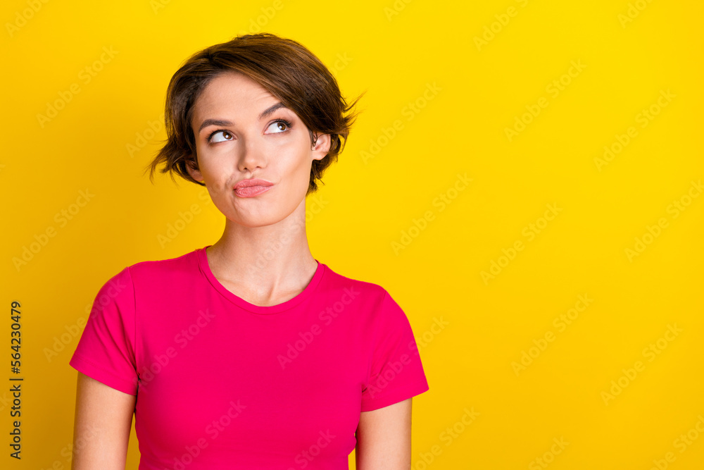 Fototapeta premium Photo of adorable doubtful lady wear pink t-shirt looking empty space isolated yellow color background