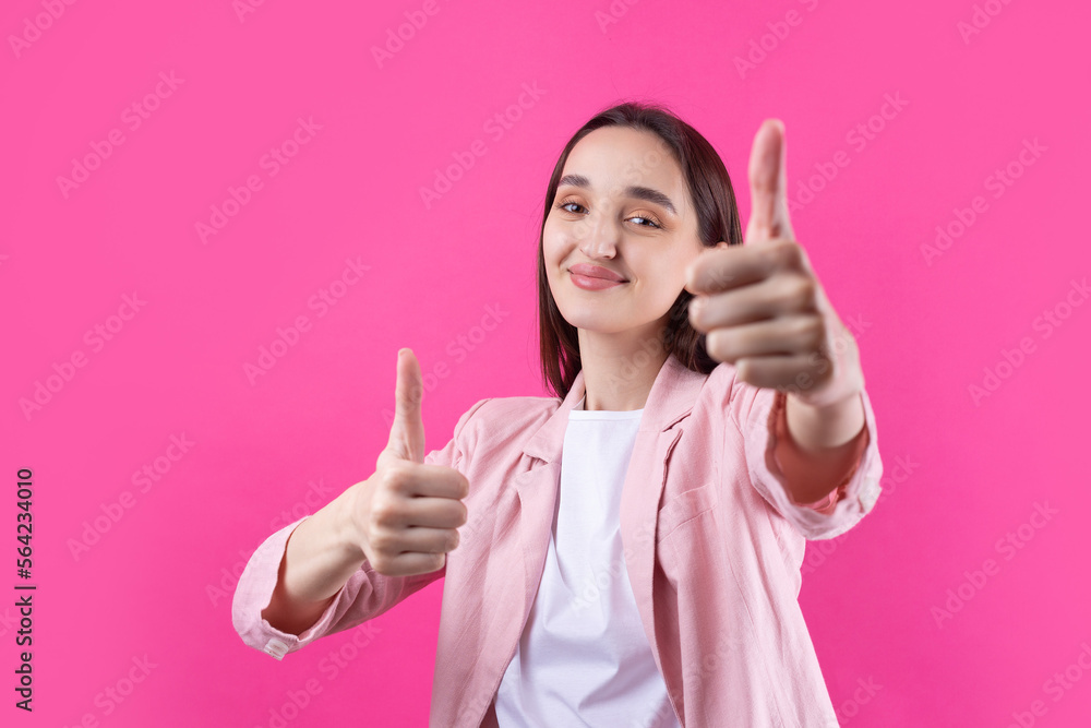 Happy young caucasian female in an pink jacket making thumb up sign and smiling. Good job and respect. Happy young caucasian female in an pink jacket making thumb up sign and smiling. Good job and respect.