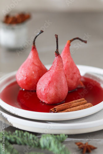 Plate with sweet poached pears in red wine on light background.