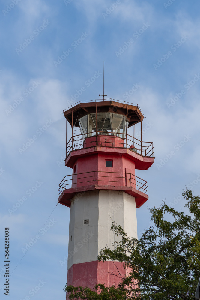 Gelendzhik. Modern lighthouse on thick cape. Multifaceted red and white column of lighthouse tower is 50 meters high against blue sky with white clouds. Close-up.
