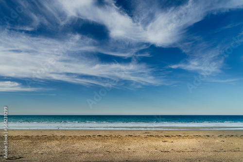 Landscape of an uncrowded beach with white clouds over blue sky in Brittany, France.