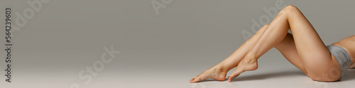 Photos Cropped image of slim smooth female legs over grey background