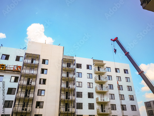 boom of a crane against the background of a high-rise residential building made of monolithic reinforced concrete. Construction of apartments in a new residential complex