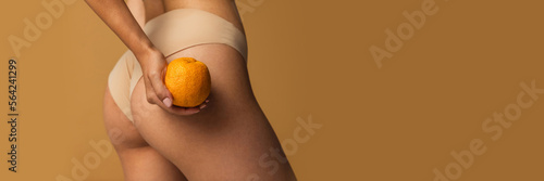 Cropped image of slim smooth female legs, buttocks with orange over light brown background. Anti-cellulite care. Concept of body, skin care, fitness, health, wellness. Banner, flyer. Copy space for ad