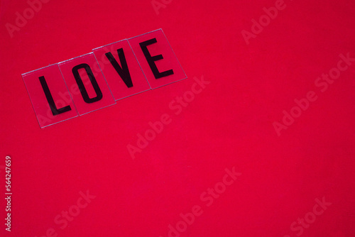 Palabra LOVE escrita con letras negras en mayuscula sobre un fondo rojo por el día de los enamorados. photo