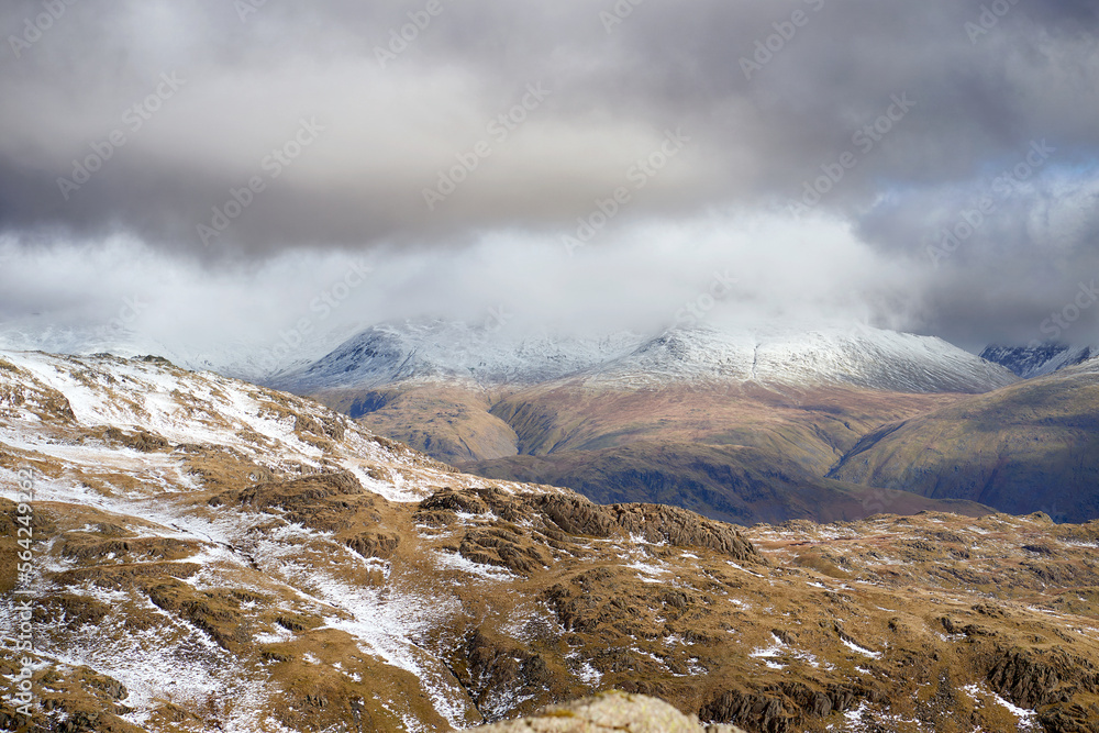 The summits of Helvellyn, Nethermost and Dolly Wagon capped in snow and cloud from Pavey Ark in the Cumbrian Lake District Mountains, England UK.