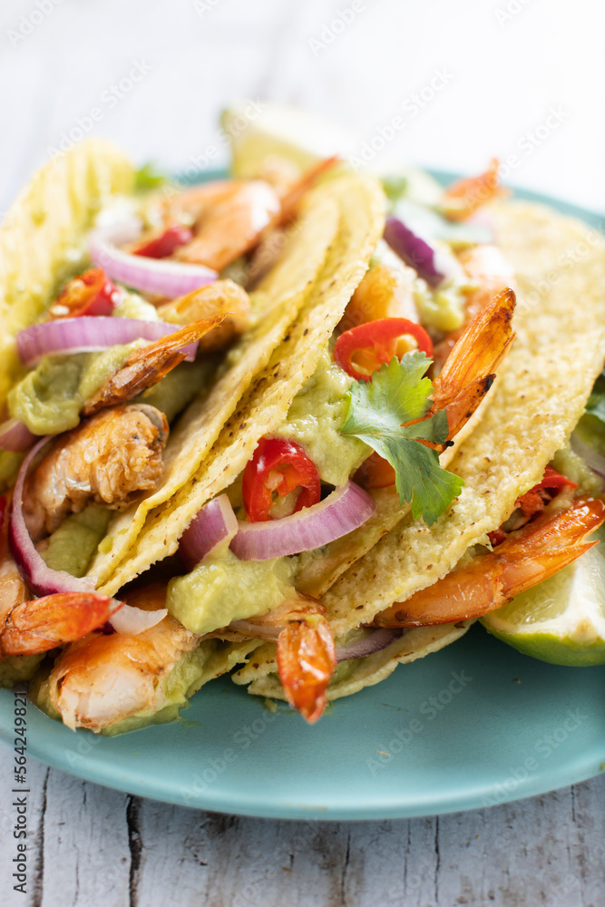 Mexican tacos with shrimp,guacamole and vegetables on wooden table Mexican tacos with shrimp,guacamole and vegetables on wooden table