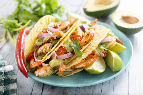Mexican tacos with shrimp,guacamole and vegetables on wooden table