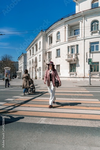 Wallpaper Mural Woman city road crossing. Stylish woman in a hat crosses the road at a pedestrian crossing in the city. Dressed in white trousers and a jacket with a bag in her hands. Torontodigital.ca