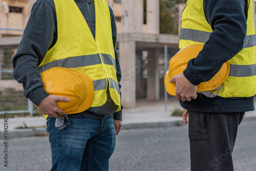 Bild auf Leinwand Detalle de dos trabajadores de obra, irreconocibles, con los cascos de seguridad en la mano, en el descanso del trabajo