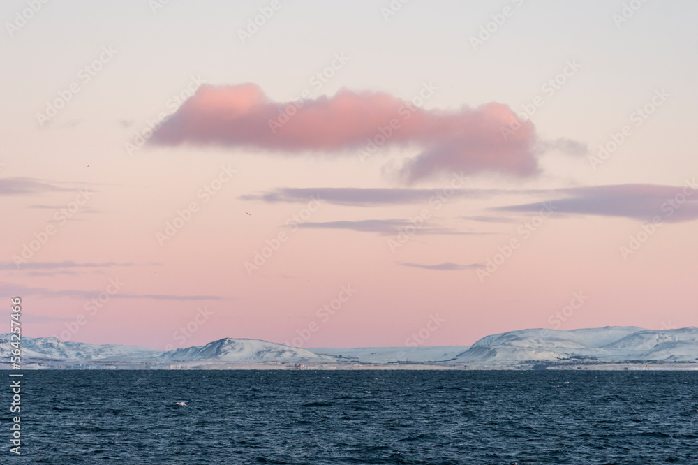 imagen de una montaña con el cielo morado con las últimas luces del día, algunas nubes y el mar en los pies 