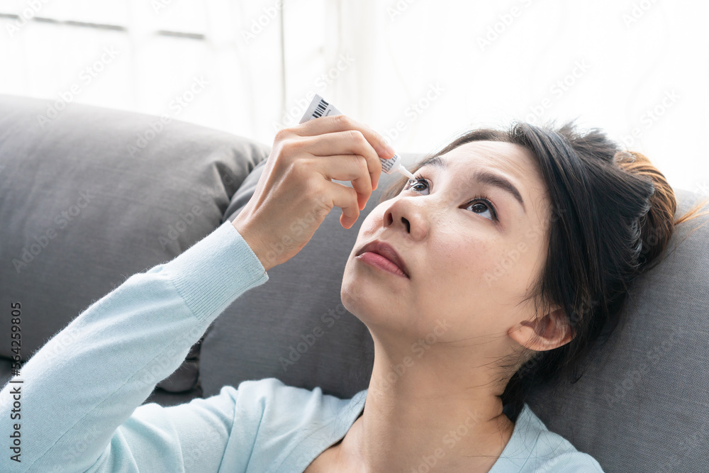 Naklejka premium Young Asian woman uses eye drops for eye treatment. Redness, dry eyes, allergy and eye itching. Vision and ophthalmology medicine concept.