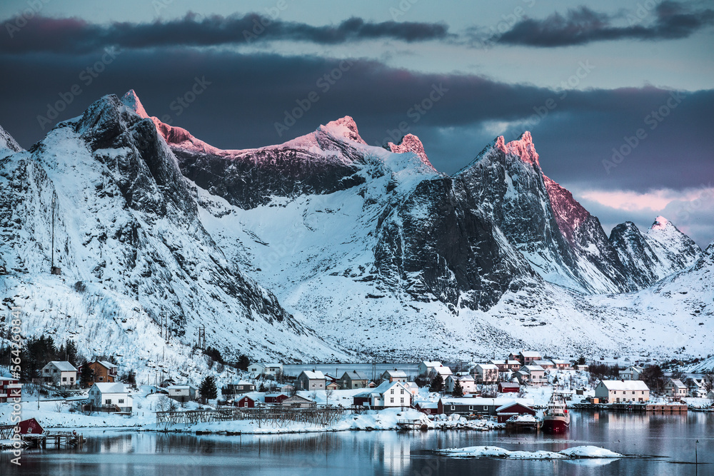 Morning sunrise in Reine, unbelievable view on small fishing village in Lofoten, Norway, Epic snowy mountains and red cabins with water, beautiful background picture from wild nature 