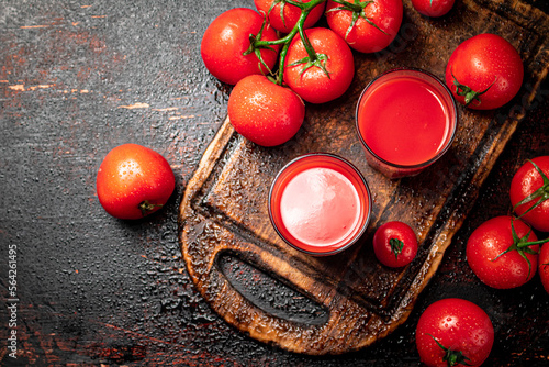Tomato juice in glasses on a wooden cutting board. 