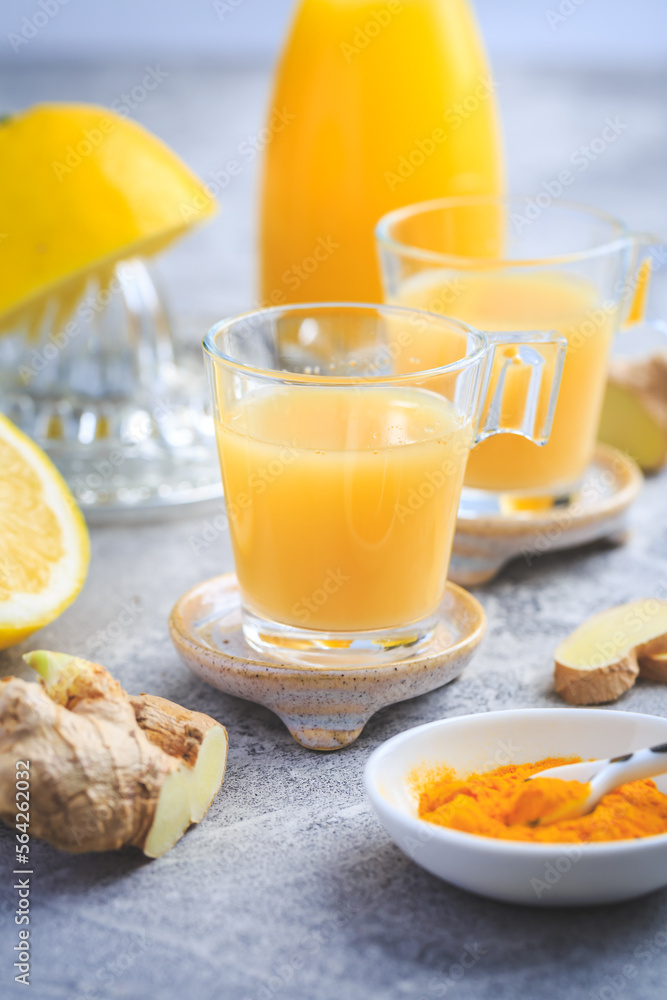 Homemade turmeric lemon ginger shots in small glasses Homemade turmeric lemon ginger shots in small glasses