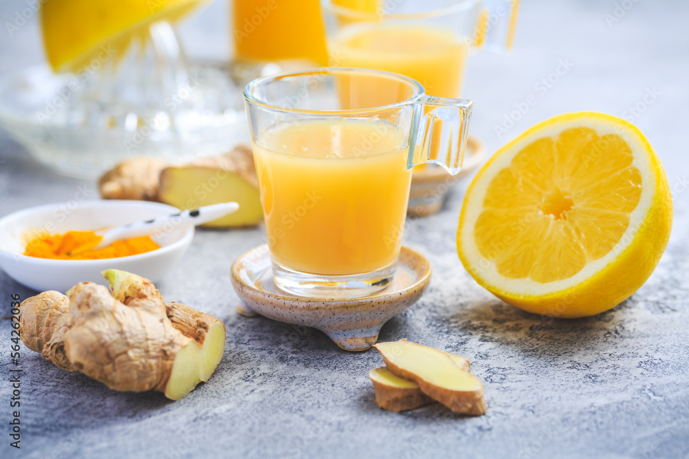 Homemade turmeric lemon ginger shots in small glasses Homemade turmeric lemon ginger shots in small glasses