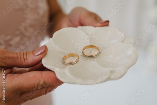 Two beautiful golden wedding rings in woman hands. Men's and women's wedding ring with ornament. Closeup.