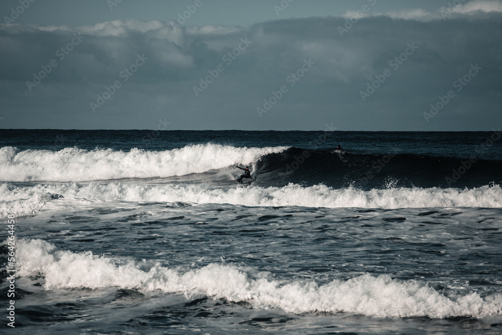 Arctic surfer in Unstad beach, Lofoten, Norway during cold winter time with big waves 