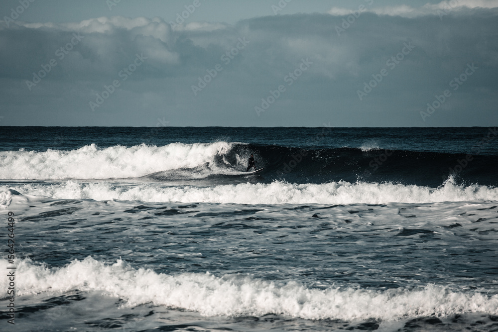Arctic surfer in Unstad beach, Lofoten, Norway during cold winter time with big waves 