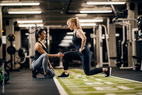 A female coach is coaching sportswoman in a gym.