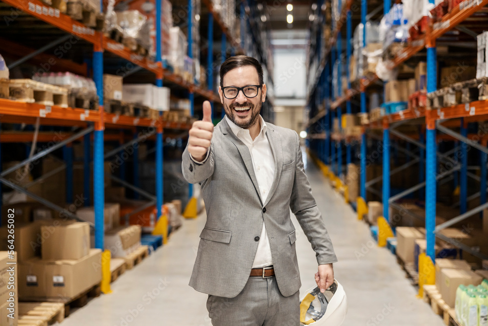 An executive stands in warehouse and giving thumbs up. An executive stands in warehouse and giving thumbs up.