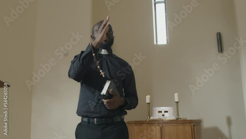 Medium portrait of modern African American Catholic pastor preaching during Sunday service in church photo