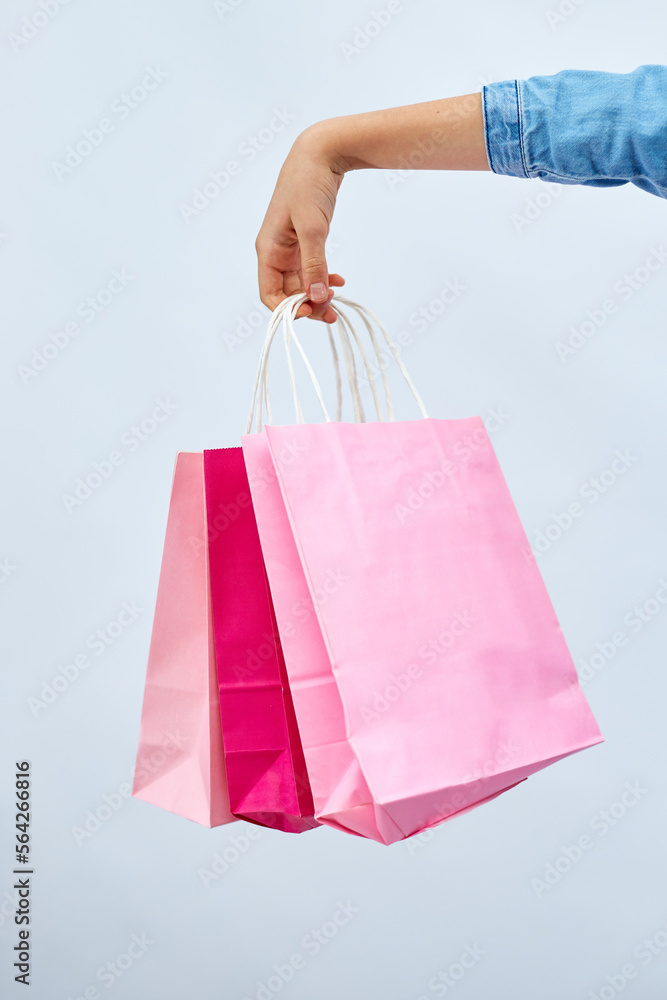 Unrecognizable child girl in casual denim dress hold in hand pink shopping bags on white background, studio, Shopaholic shopping and fashion, discount sale concept, copy space, banner. Black friday