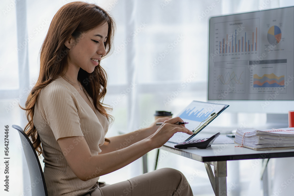 Asian businesswoman working with financial documents and desktop computer in office calculating financial indicators smiling and happy with success and results of business success Asian businesswoman working with financial documents and desktop computer in office calculating financial indicators smiling and happy with success and results of business success