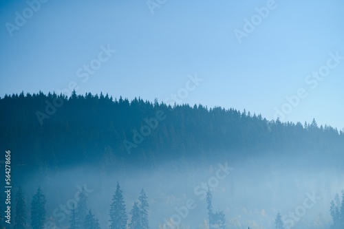 Mountain range with visible silhouettes through the morning blue fog.