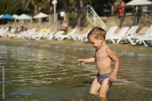 Fototapeta Naklejka Na Ścianę i Meble -  Happiness boy fun on the beach under sunset sunlight in summer suny day. The kid cheerfully runs into the sea.