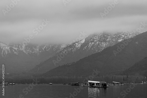 Kashmir, Srinagar India - Jan 10 2023: Popular Srinagar Houseboats in Dal Lake. Colorful Shikara ride floating in Dal Lake aka Nigeen lake. Mountain range in Srinagar. Couple Honeymoon Destination. 