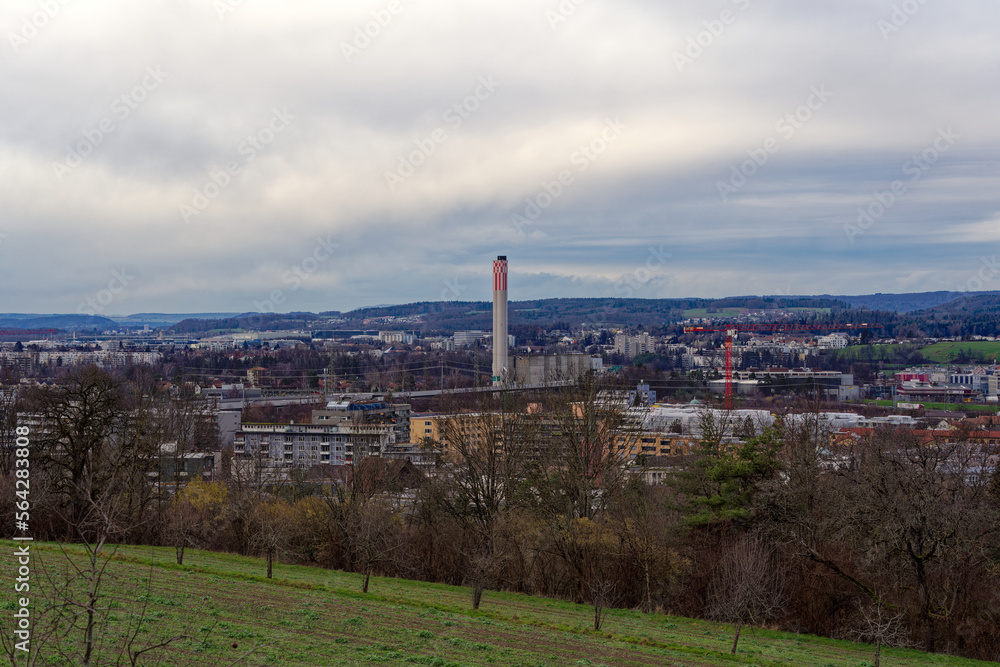 Meadow with apple trees and farm and skyline in the background at City of Zürich district Schwamendingen on a cloudy winter day. Photo taken January 14th, 2023, Zurich, Switzerland.