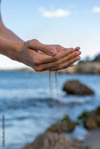 Young man hands pouring sand at the beach