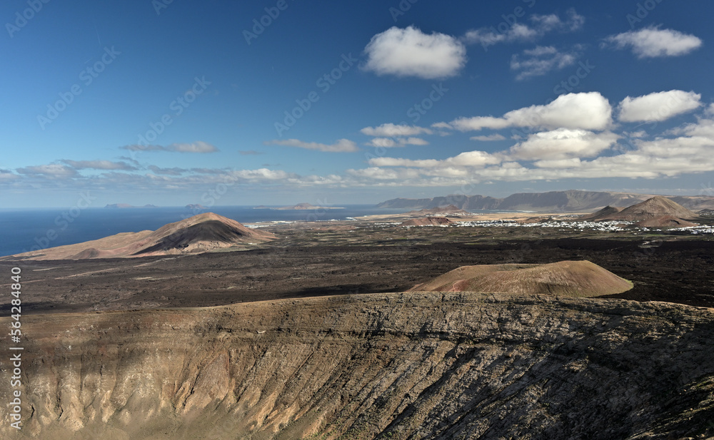 Obraz premium Ein Panoramablick von der Caldera Blanca über die Kanareninsel Lanzarote mit seinen Vulkanen, Lavafelder, Ortschaften bis hin zum Meer.