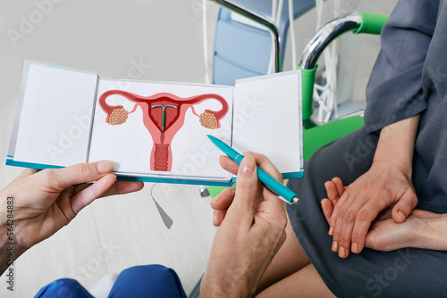 IUD. Experienced gynecologist showing female patient intrauterine contraceptive device or coil to prevent pregnancy while consultation photo