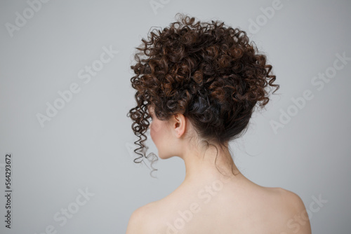 Elegant hairstyle of curls on the head of a white woman isolated on a gray background.