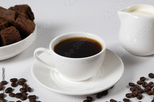 Coffee with milk - a cup of coffee and a milk jug on a white background, a place for text, a delicious breakfast.