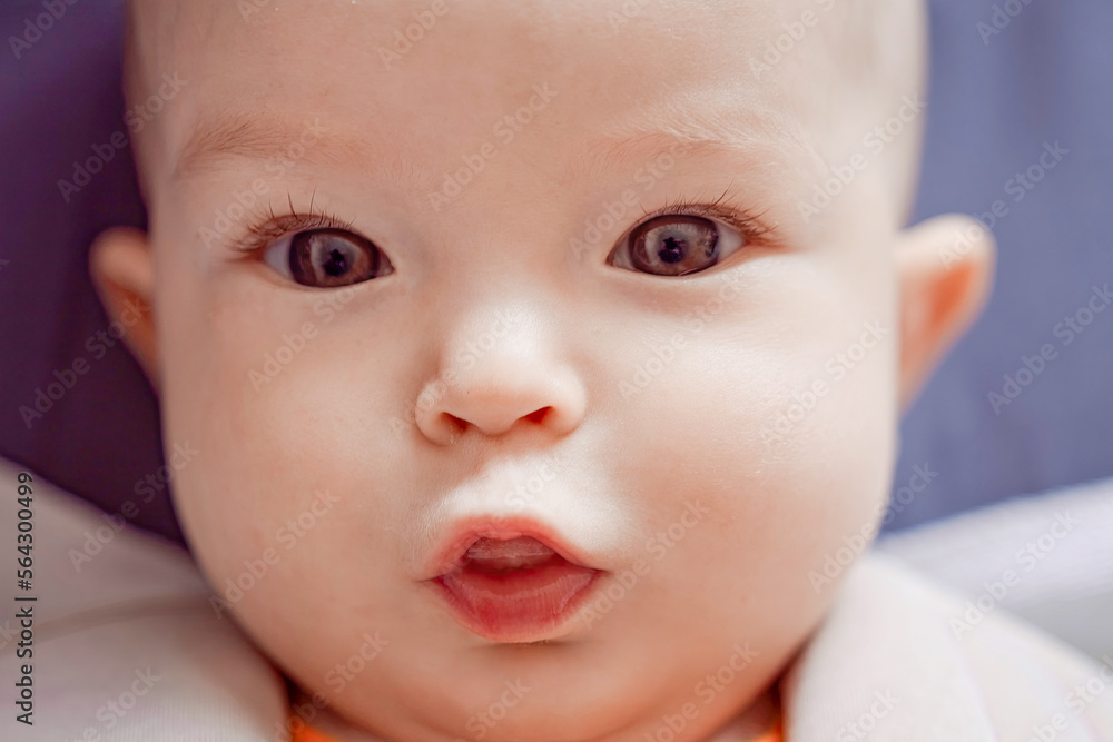 Close-up portrait of a happy baby. The plump face of a newborn with a blissful smile. Sweet smile of a calm child