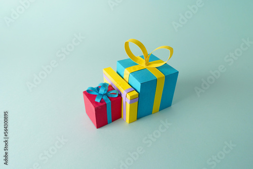 Fototapeta Naklejka Na Ścianę i Meble -  Paper cutout of isolated presents for birthdays, valentines day or Christmas over a minimalistic background, group of gifts with ribbon using papercraft art