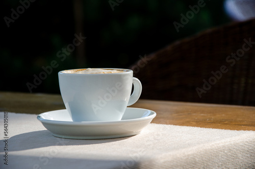 Coffee cup on wood table nature background in garden.