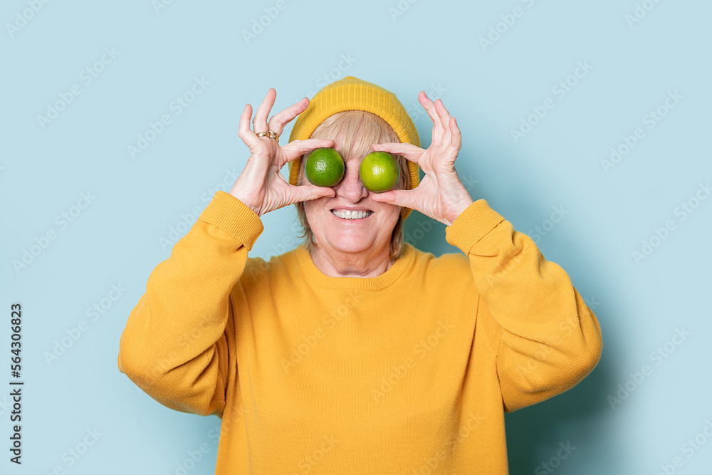 Senior woman covering eyes with limes Senior woman covering eyes with limes