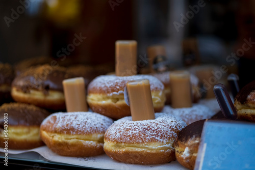 Berliner Pfannkuchen, a German donut, traditional yeast dough deep fried filled with chocolate cream or strawberry marmalade and sprinkled with powdered sugar in showcase. Selective Focus.