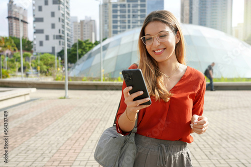 Brazilian young business woman using smartphone in Brooklin modern district of Sao Paulo metropolis, Brazil photo